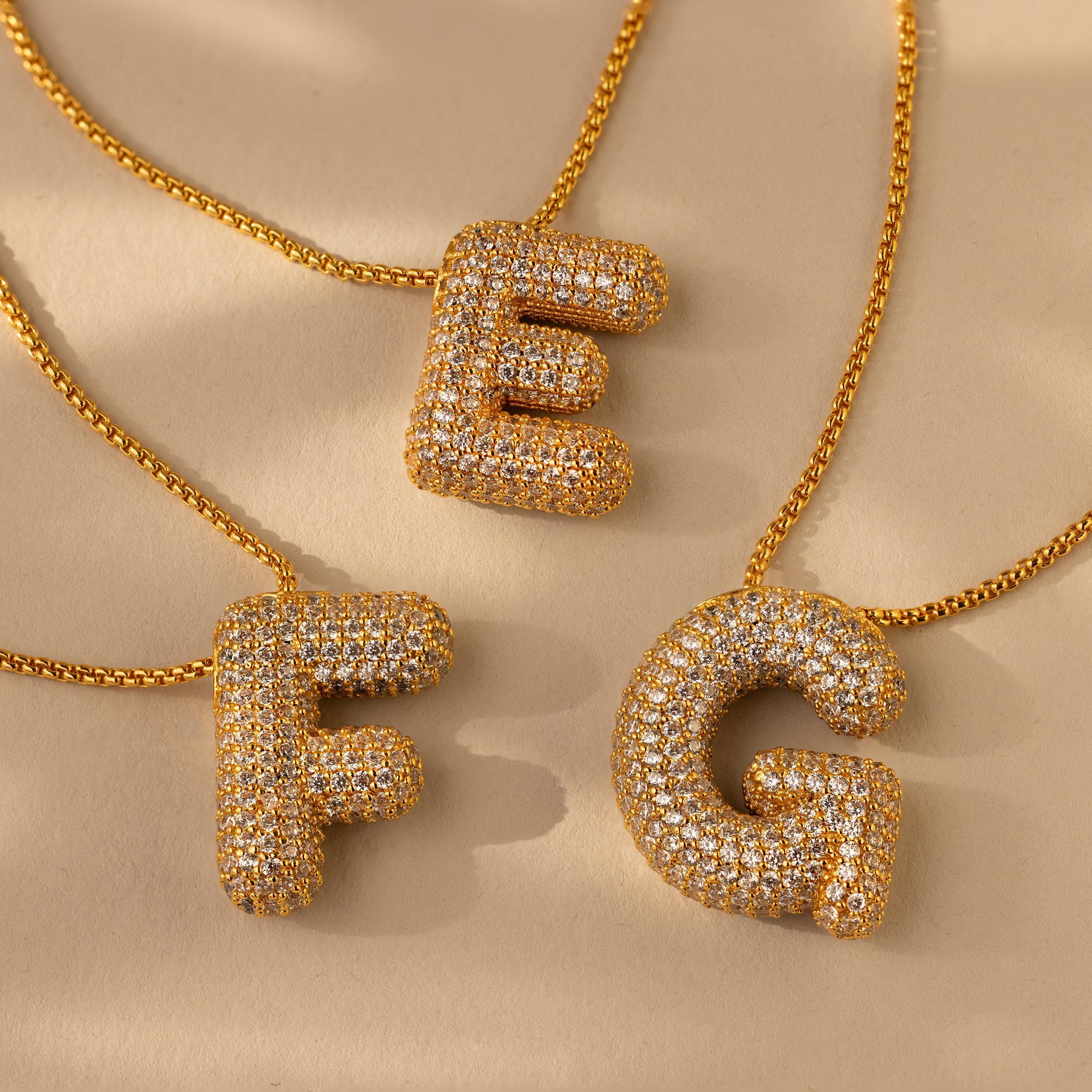 Three 18K gold pave CZ diamond puffy initial necklaces on a gold chain, with the letters 'F', 'E', and 'G'.